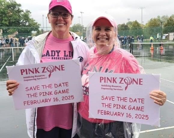 Two women in pink holding signs.